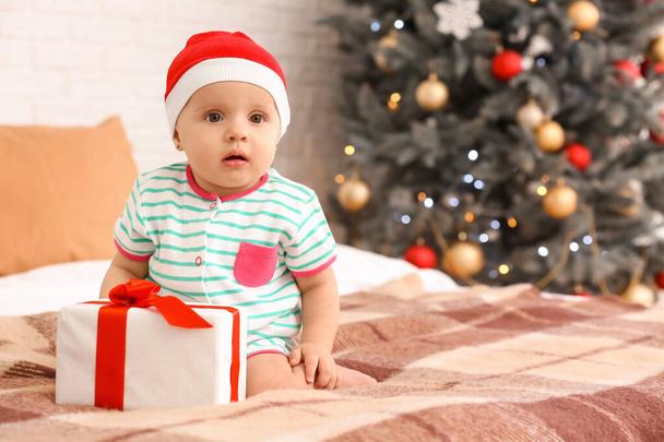 Cute little baby z Santa Claus kapelusz i prezent w pokoju urządzone na Boże Narodzenie - Zdjęcie, obraz
