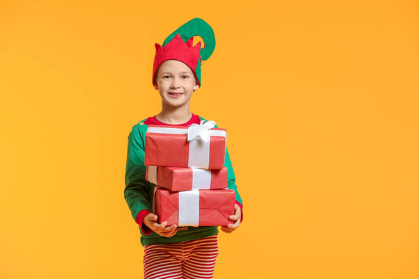 Little boy in costume of elf and with gifts on color background - Fotografie, Obrázek