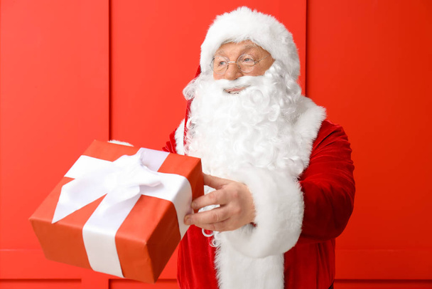 Santa Claus with gift on color background - Foto, imagen