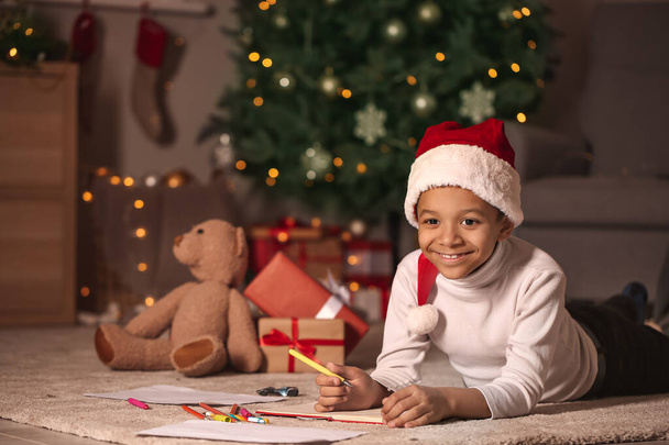 Cute African-amerykański chłopiec pisząc list do Świętego Mikołaja w Wigilię Bożego Narodzenia w domu - Zdjęcie, obraz