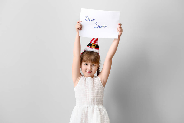 Милая маленькая девочка с письмом к Санта-Клаусу на белом фоне
 - Фото, изображение