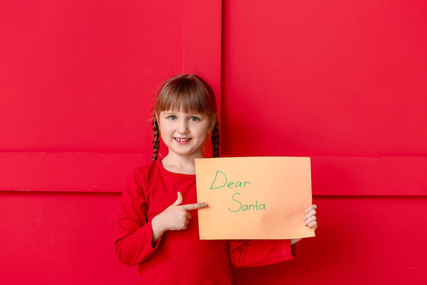 Cute little girl with letter to Santa Claus on color background - Foto, Bild