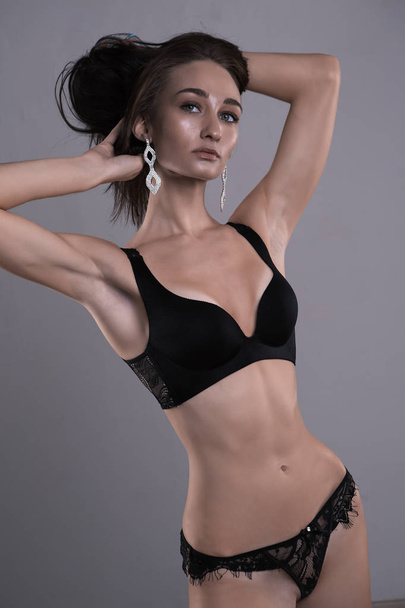 beautiful sexy brunette in black erotic lingerie on grey isolated background - Valokuva, kuva