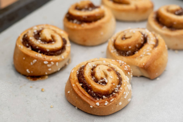 Freshly baked cinnamon buns rolls on a tray lined with baking parchment paper - Φωτογραφία, εικόνα