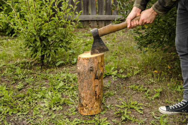 Lumberjack chopping wood. Young man chopping woods with an axe - Fotó, kép