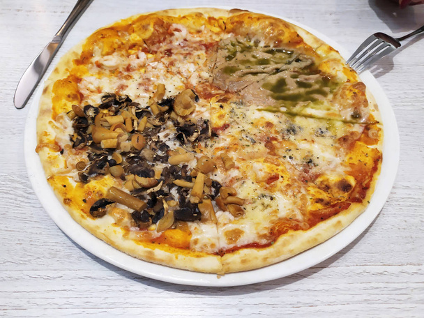 Świeże plastry pizzy z serem, grzybami i mięsem na białym talerzu na drewnianym tle stołu. - Zdjęcie, obraz