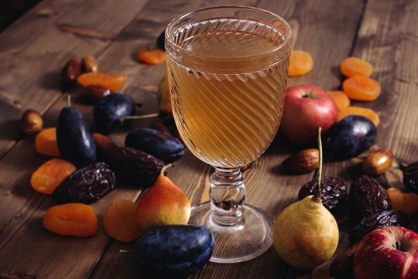 A glass cup with apricot apple plum pear fruit compote and ripe apricots on a wooden table. Sweet and healthy dessert. - Photo, Image