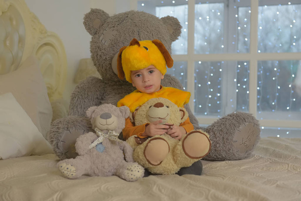 boy in carnival costume of a dog surrounded by toy bears sitting - Photo, Image