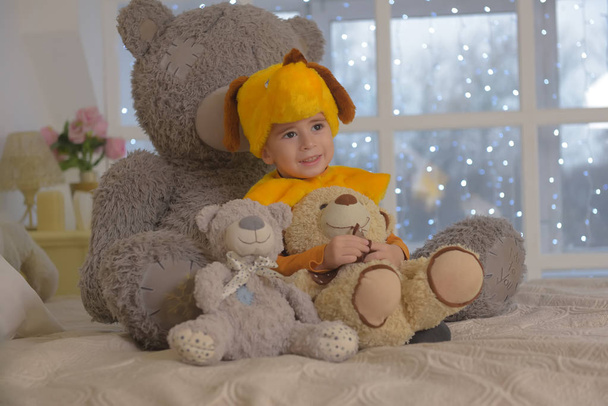 boy in carnival costume of a dog surrounded by toy bears sitting - Foto, Bild