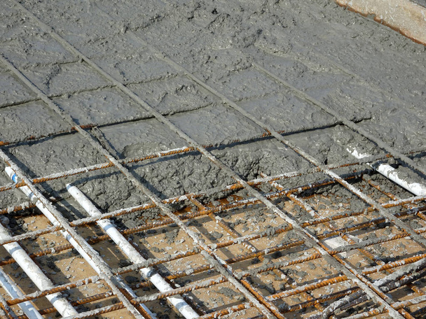 鉄筋コンクリート床スラブと呼ばれる強力な床スラブを形成するために鋼補強棒に注いだ湿式コンクリート.  - 写真・画像