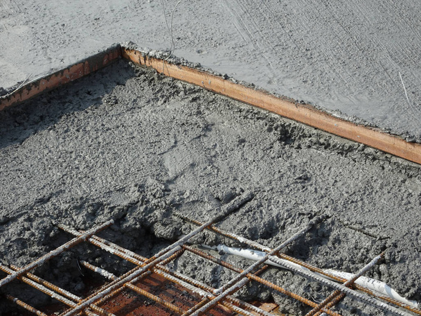 der nasse Beton, der auf eine Stahlbewehrungsstange gegossen wurde, um starke Bodenplatten zu bilden, die als Stahlbetonbodenplatte bezeichnet werden.  - Foto, Bild