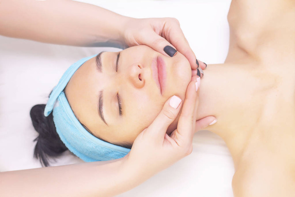 Young woman enjoying massage in spa salon. Face massage. Closeup of young woman getting spa massage treatment at beauty spa salon.Spa skin and body care. Facial beauty treatment.Cosmetology.  - Photo, image