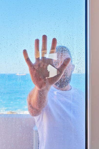 Caucasian man with raised hand through window glass - Photo, image