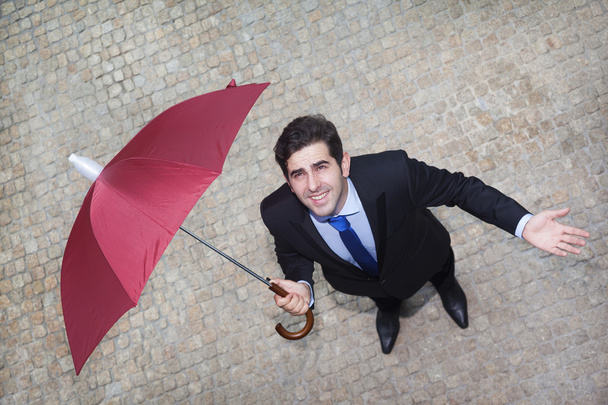 Confident businessman looking to the sky and checking if it's raining - Foto, Imagem