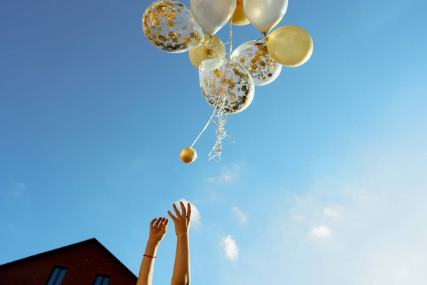 желтые и белые прозрачные воздушные шары голубое небо с детьми руками
 - Фото, изображение