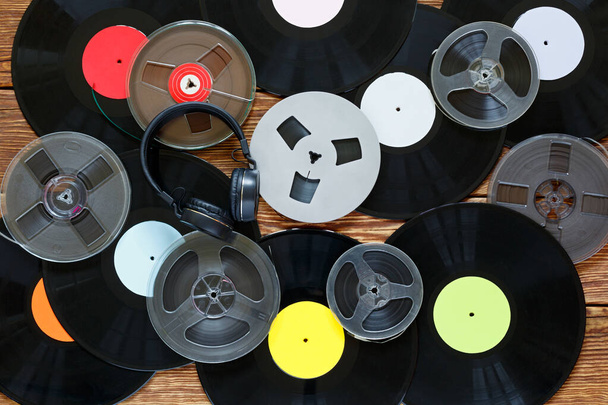 alte Vintage-Klöppel, Schallplatten, Kassetten und Kopfhörer auf einem Holztischhintergrund. Bunte Etiketten. Ansicht von oben. - Foto, Bild