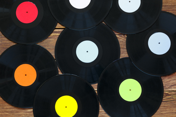 Retro vinyl discs records on wood table background. Multicolored labels. Top view. - Фото, изображение
