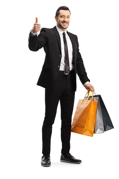 Young businessman with shopping bags showing a thumb up - Fotoğraf, Görsel
