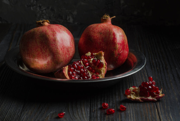 Two pomegranates lie on a metal plate, - Foto, afbeelding