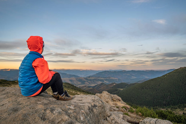 Fiatal gyermek fiú túrázó ül a hegyekben élvezi a kilátást amaz - Fotó, kép