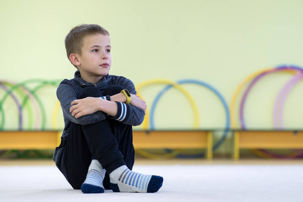 Fiatal gyermek fiú ül és relaxációg a padlón belül sport - Fotó, kép