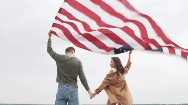 Happy couple holding the American flag in nature. Independence Day, lifestyle, travel concept - Felvétel, videó