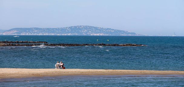 Θέα στη θάλασσα με μοναχικό ζευγάρι να κάθεται στις καρέκλες και να βλέπει τη θάλασσα - Φωτογραφία, εικόνα