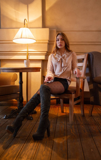 Una joven y bonita mujer en la cafetería. Grunge. Chica en un café en una blusa beige
 - Foto, Imagen