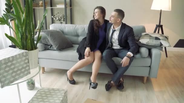 Happy couple relaxing after moving things to a new apartment, discussing interior design for new home. - Materiał filmowy, wideo