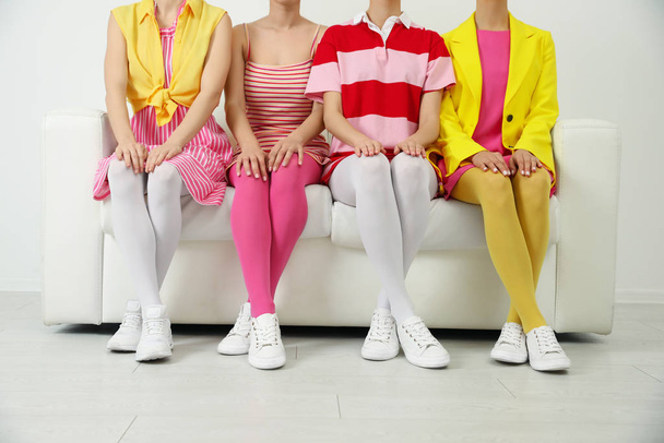 Women wearing colorful tights sitting on sofa indoors, closeup - Foto, afbeelding