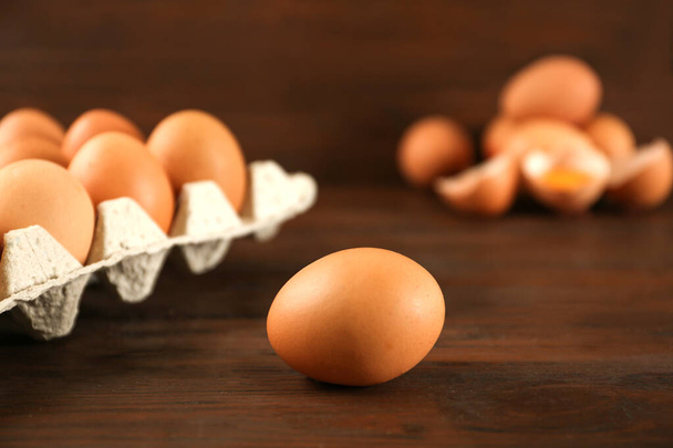 Raw chicken egg near carton tray on wooden table - Фото, изображение