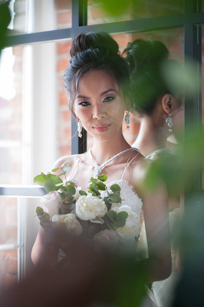 Азиатская невеста с цветами в белом платье
 - Фото, изображение