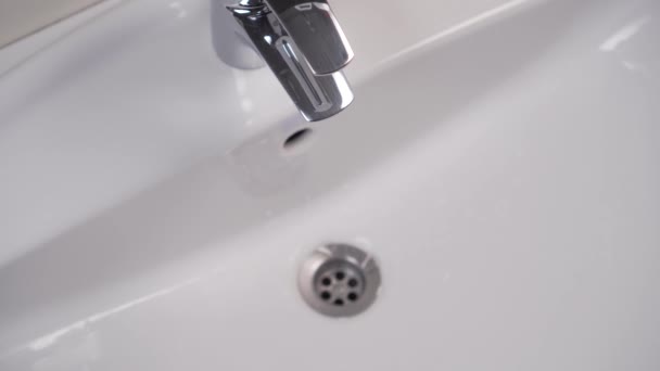 Assemblage d'un filtre avec un joint en caoutchouc sur un robinet de toilette public brillant après le nettoyage. Lavabo blanc propre. Entretien de la plomberie. La main d'un serrurier enroule un détail
 - Séquence, vidéo