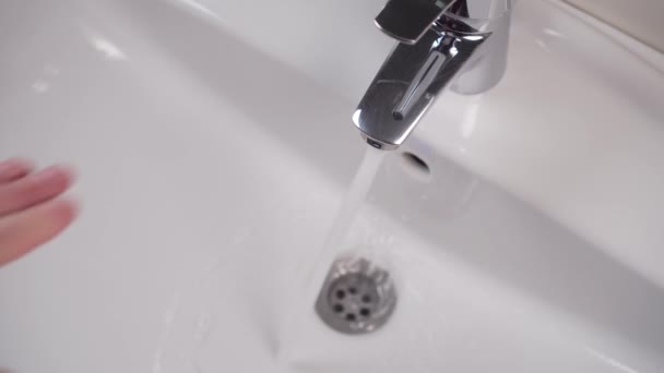 A mans hand closes a faucet in a white bathroom sink and tap water stops pouring. White clean sink.  - Footage, Video