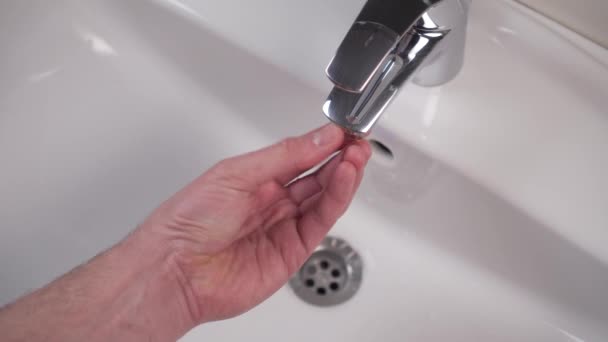 Installation and inspection of the filter with rubber gasket of the shiny bathroom faucet after cleaning. White clean sink. Plumbing maintenance. Hand locksmith winds the part and turns on the water - Footage, Video