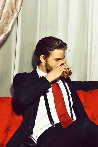 bearded man, businessman holding glass of whiskey in red tie - 写真・画像