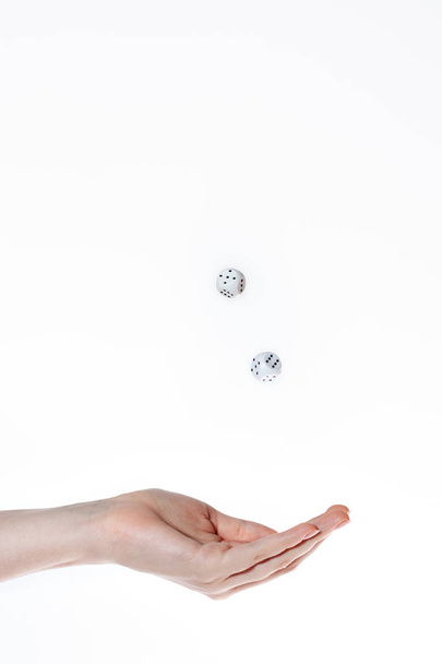 Hand rolls and catches two dice on a white background, concept of risk and good luck - Фото, изображение