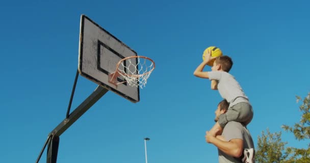Πατέρας και γιος απολαμβάνουν ένα παιχνίδι μπάσκετ. - Πλάνα, βίντεο