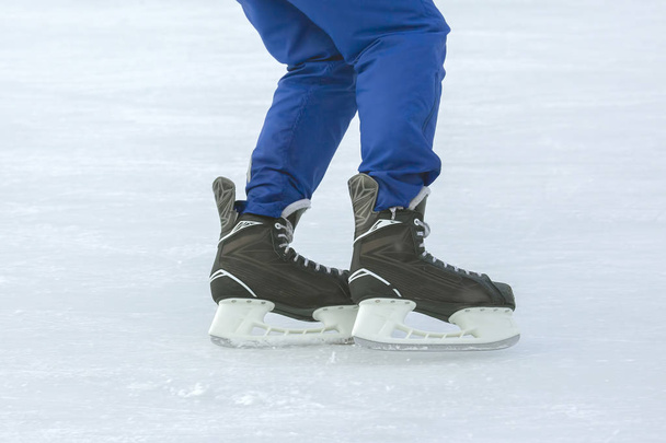 Beine eines Mannes, der auf einer Eisbahn Schlittschuh läuft. Hobbys und Sport. Vakanzen - Foto, Bild
