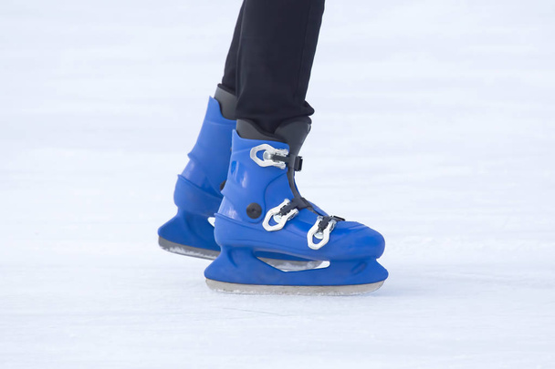 legs of a man in blue skates rides on an ice rink. Hobbies and s - Photo, Image
