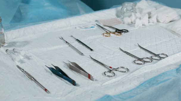 Koncepce medicíny, chirurgie. Pracovní stůl s nástrojem pro chirurgický zákrok, Closeup, modrý světlo. Na stole se rozprostře sterilny nástroje chirurgů, skalpelů, sponek, tampónů, injekční stříkačky. - Záběry, video