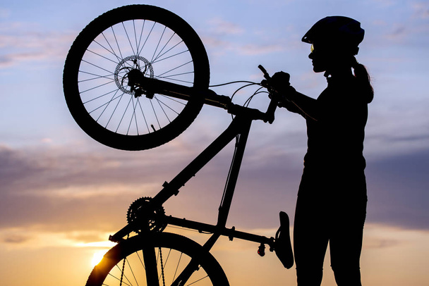 Sziluett egy lány kerékpáros kerékpárral a háttérben - Fotó, kép