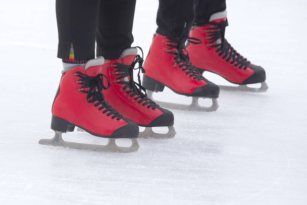 voeten in rode schaatsen op een ijsbaan. Hobby 's en sport. Vakantie - Foto, afbeelding