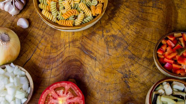 frische Zutaten zum Kochen: Nudeln, Tomaten, Zwiebeln, Paprika, Auberginen und Knoblauch - Foto, Bild