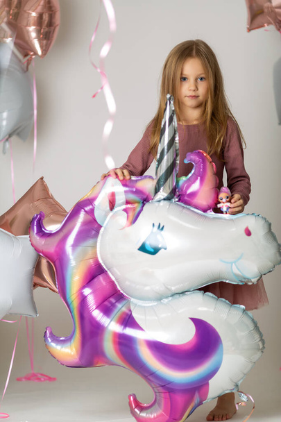 blonde girl with blue eyes in a dress holds a large helium unicorn ball - Valokuva, kuva