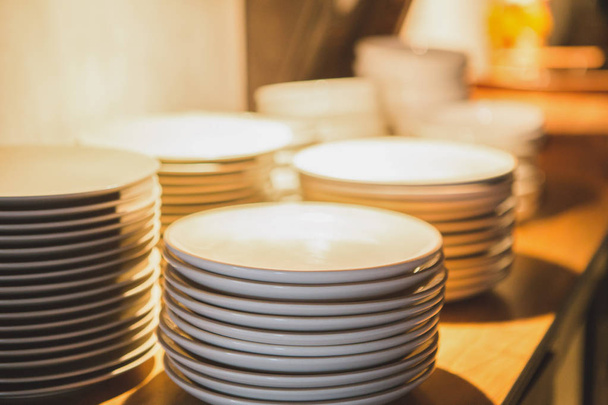 Белая тарелка, сложенная на столе на вольфрамовом свете
 - Фото, изображение