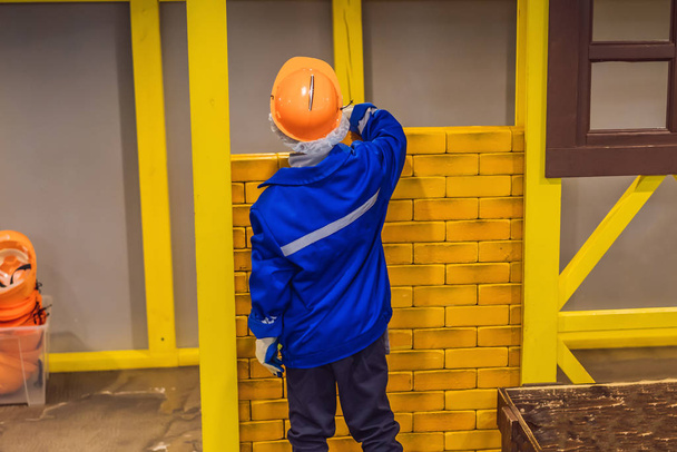 Хлопчик грає у будівельнику в будівельному одязі та шоломі
 - Фото, зображення