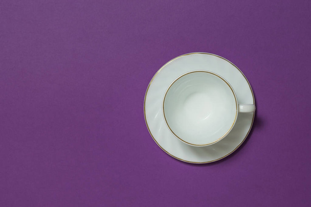 Taza de café de cerámica blanca sobre fondo lila. Puesta plana
. - Foto, Imagen