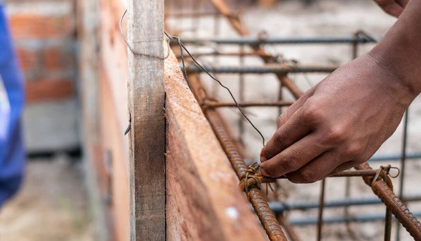 A worker using steel wire and pincers to secure steel bars, prep - Photo, Image
