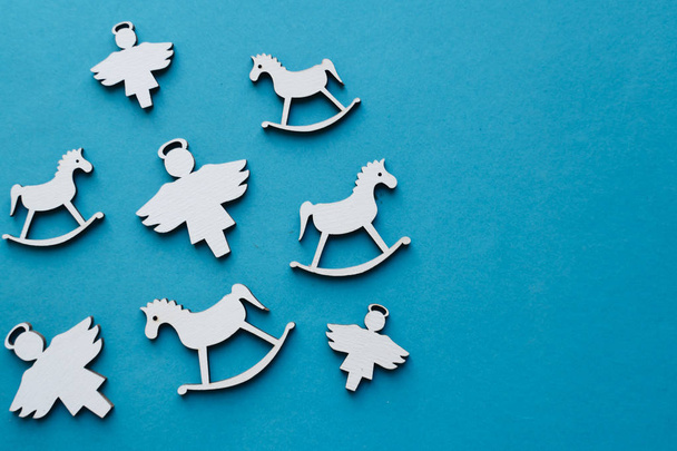 juguetes de Navidad de madera blanca sobre fondo azul, caballos y ángeles
 - Foto, imagen